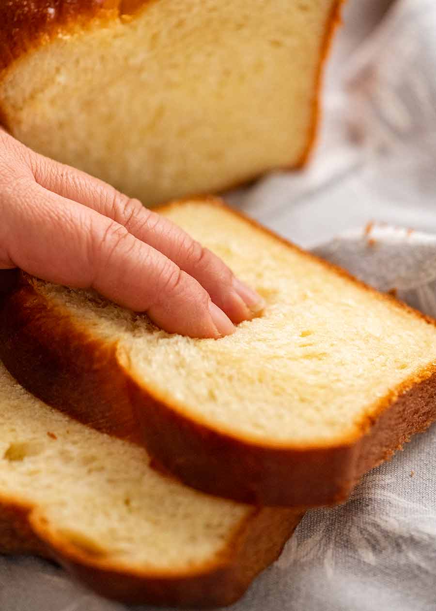 Hand touching brioche to show how soft it is