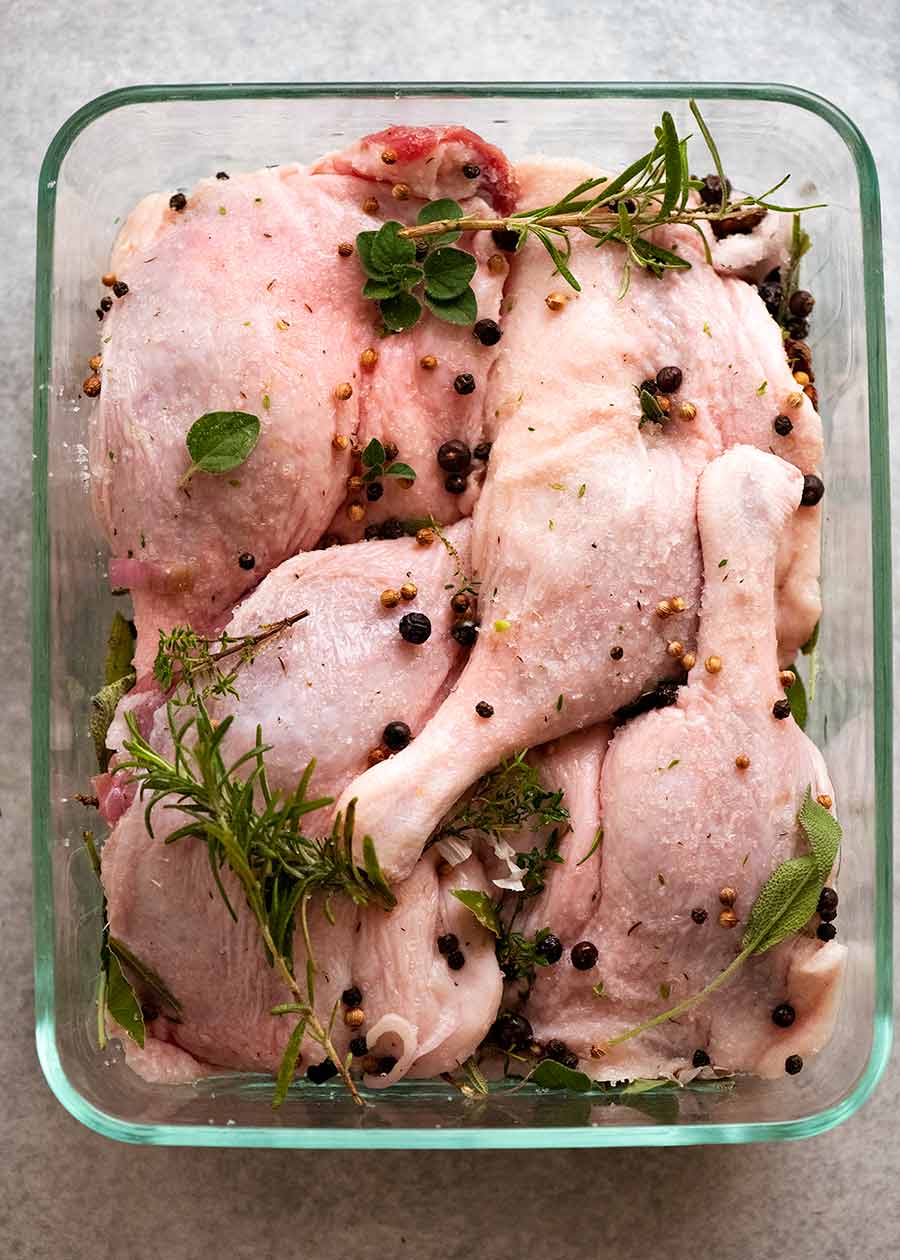 Duck Confit being marinated in fresh herbs and spices
